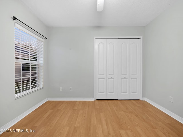 unfurnished bedroom with ceiling fan, a textured ceiling, light hardwood / wood-style floors, and a closet