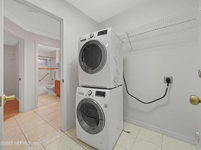 laundry area featuring stacked washer / drying machine and light tile patterned floors