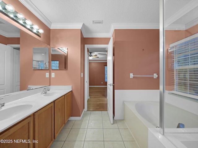 bathroom featuring crown molding, a textured ceiling, vanity, a tub, and tile patterned flooring