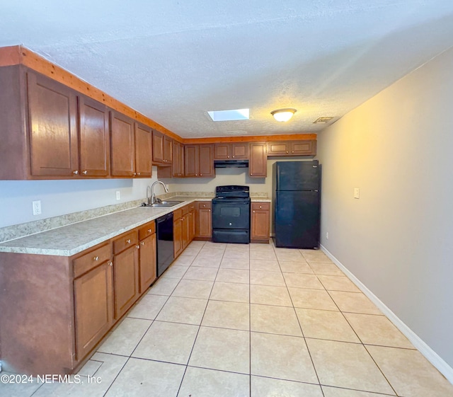 kitchen with a skylight, sink, light tile patterned floors, black appliances, and a textured ceiling