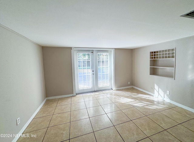 tiled empty room featuring built in features and french doors