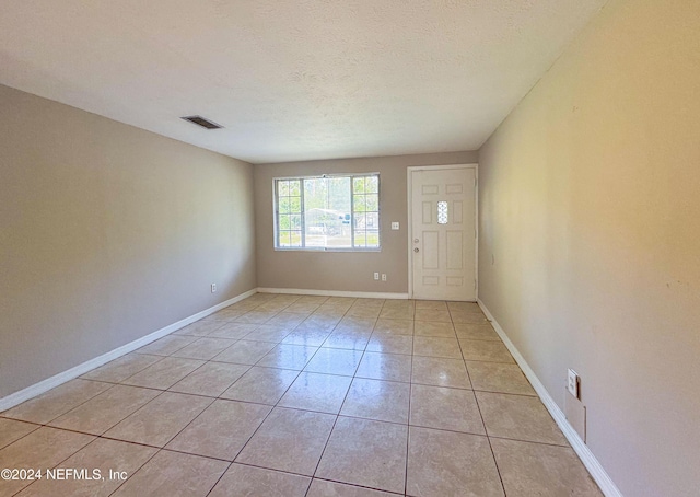 foyer with a textured ceiling and light tile patterned floors