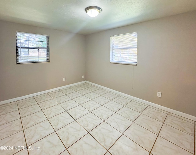 spare room featuring light tile patterned floors and a textured ceiling