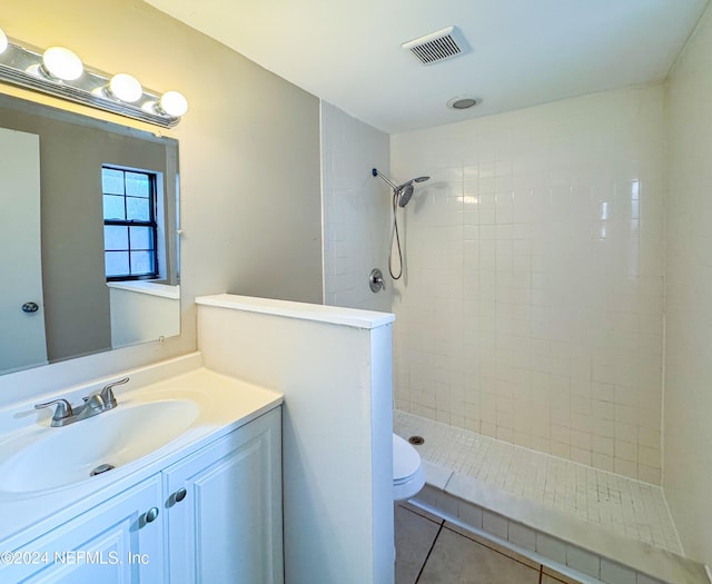 bathroom featuring vanity, a tile shower, tile patterned floors, and toilet