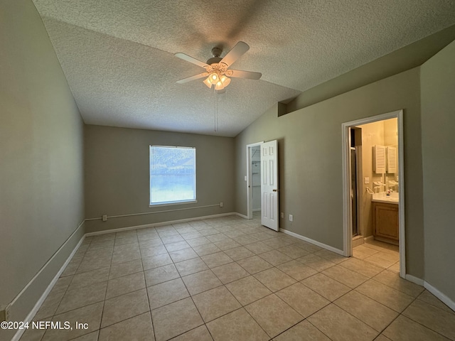 unfurnished bedroom featuring connected bathroom, ceiling fan, lofted ceiling, and light tile patterned flooring