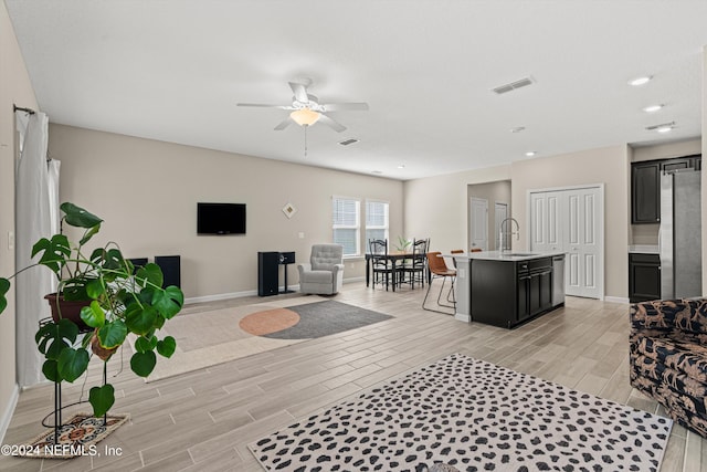 living room with ceiling fan, light wood-type flooring, and sink