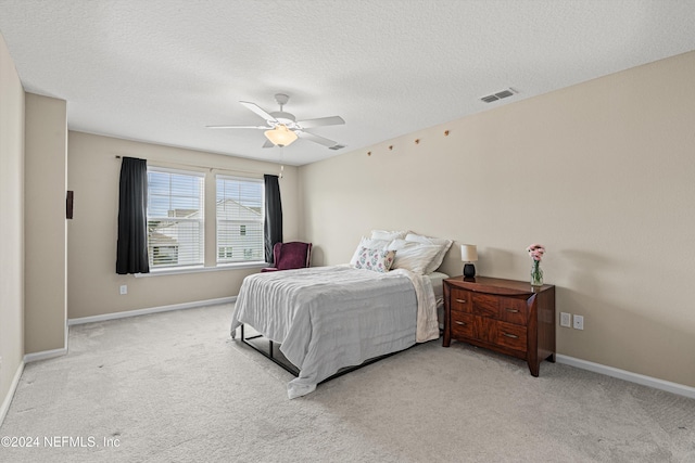 carpeted bedroom with ceiling fan and a textured ceiling