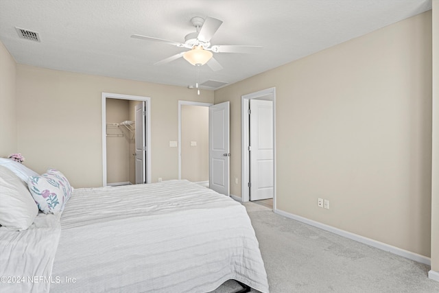 carpeted bedroom with ceiling fan, a spacious closet, a textured ceiling, and a closet