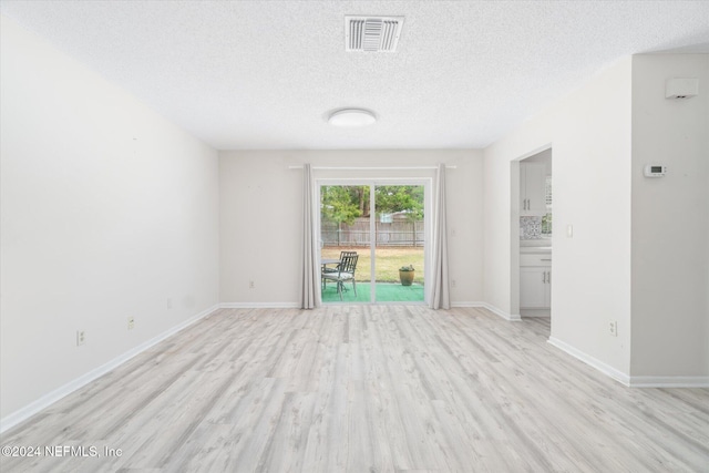 unfurnished room with a textured ceiling and light hardwood / wood-style floors