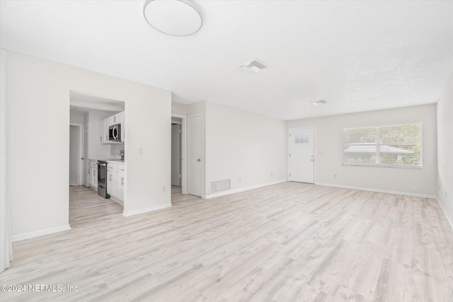 unfurnished living room featuring light hardwood / wood-style floors and a textured ceiling