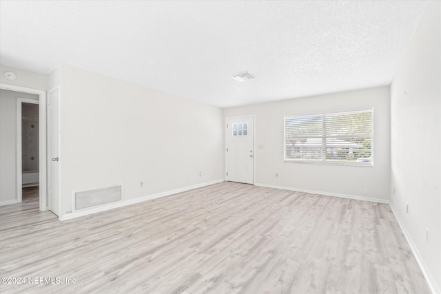 spare room featuring a textured ceiling and light hardwood / wood-style flooring