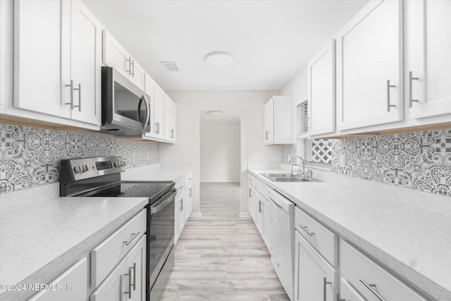 kitchen featuring decorative backsplash, stainless steel appliances, sink, light hardwood / wood-style floors, and white cabinetry