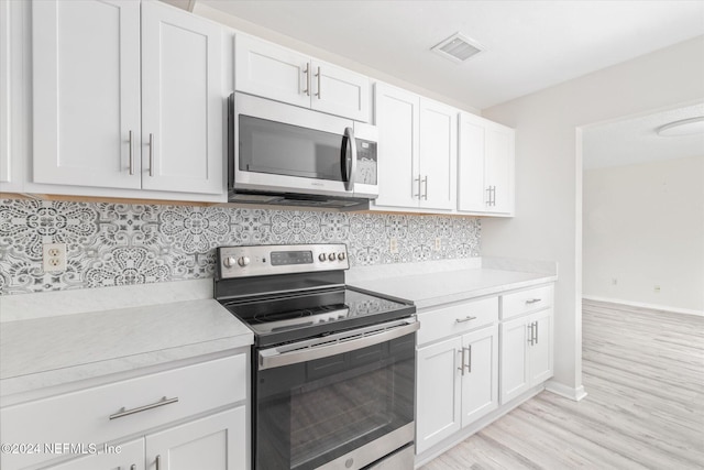 kitchen with tasteful backsplash, white cabinets, light wood-type flooring, and appliances with stainless steel finishes