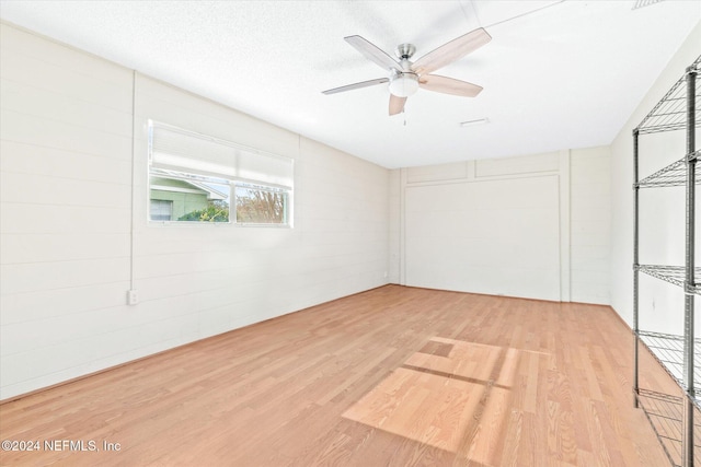 empty room with ceiling fan, a textured ceiling, and light hardwood / wood-style flooring