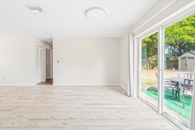 spare room featuring a textured ceiling and light hardwood / wood-style flooring