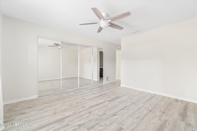 unfurnished bedroom featuring ceiling fan, light hardwood / wood-style floors, a textured ceiling, and a closet