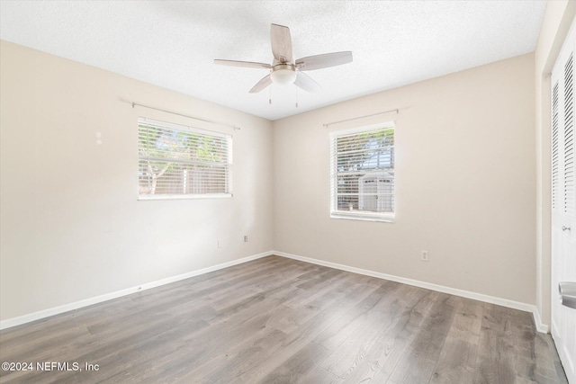 unfurnished bedroom featuring hardwood / wood-style flooring, ceiling fan, a closet, and multiple windows