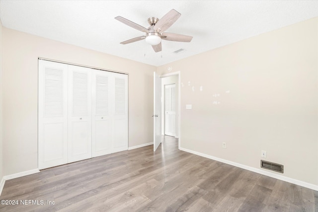 unfurnished bedroom featuring ceiling fan, a closet, a textured ceiling, and light hardwood / wood-style flooring