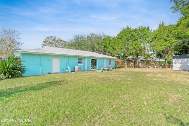 rear view of house featuring central air condition unit and a lawn