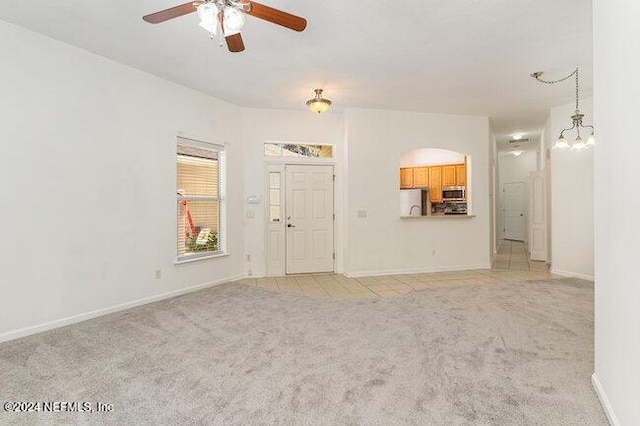 unfurnished living room with light carpet and ceiling fan with notable chandelier