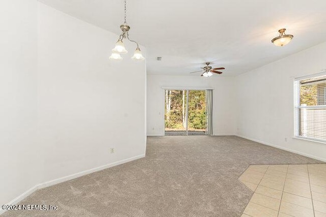 spare room featuring ceiling fan with notable chandelier and light colored carpet