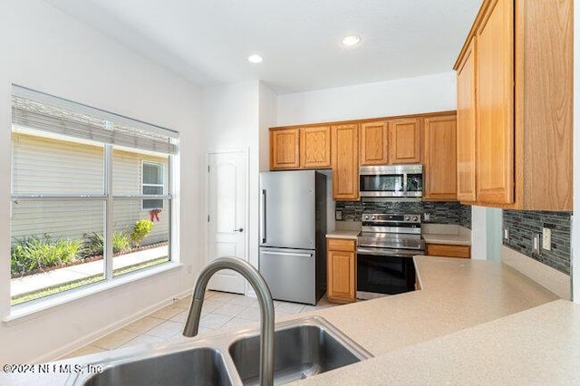 kitchen featuring backsplash, sink, light tile patterned floors, and appliances with stainless steel finishes