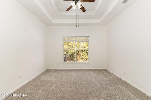 spare room featuring light carpet, a raised ceiling, and ceiling fan