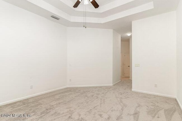 carpeted empty room with a raised ceiling and ceiling fan