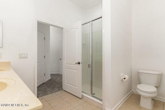 bathroom featuring tile patterned flooring, vanity, a shower with shower door, and toilet