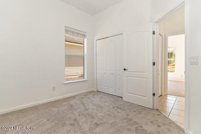 unfurnished bedroom with light carpet and a closet