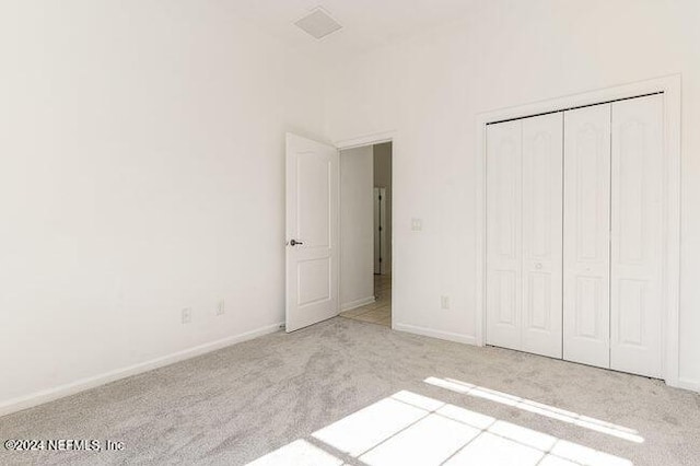 unfurnished bedroom featuring light colored carpet and a closet