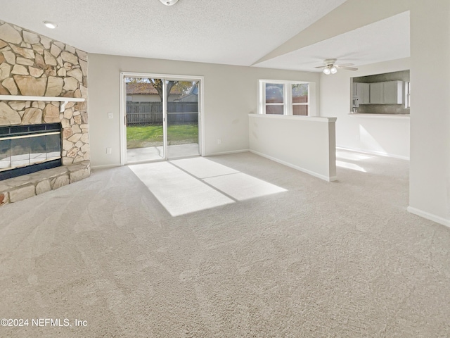 unfurnished living room featuring a textured ceiling, a fireplace, ceiling fan, and light carpet