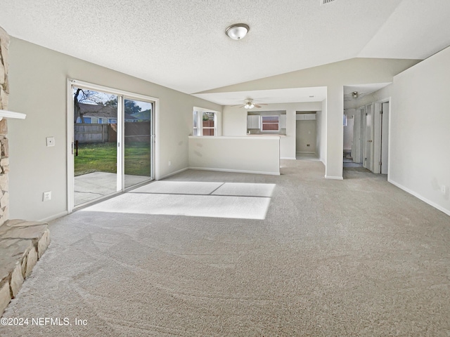 unfurnished living room with ceiling fan, light colored carpet, a textured ceiling, and vaulted ceiling