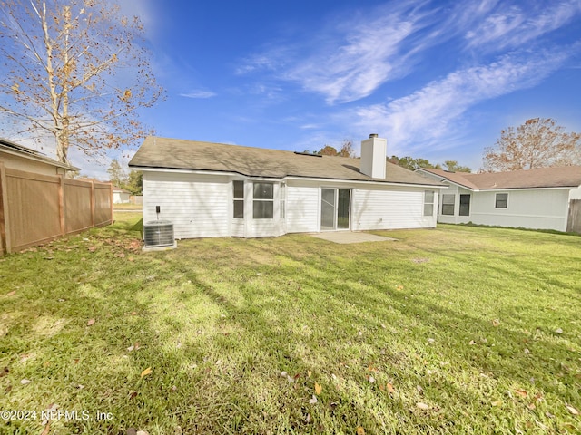 rear view of property featuring cooling unit and a yard