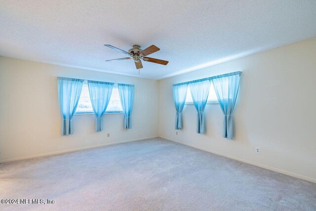 unfurnished room featuring a textured ceiling, light colored carpet, and ceiling fan