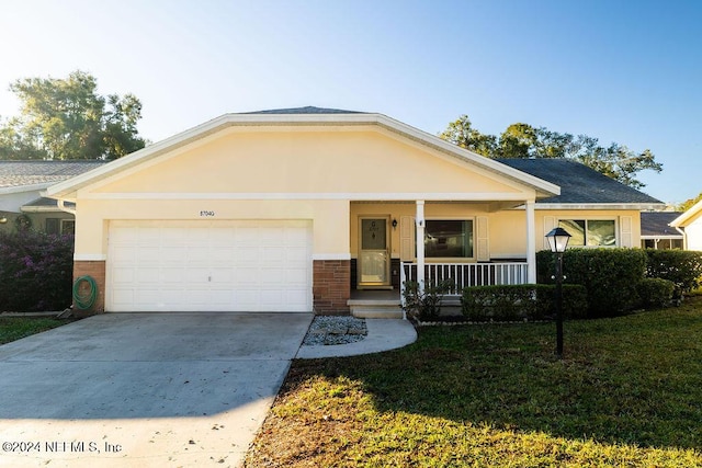 view of front of home featuring covered porch, a garage, and a front lawn