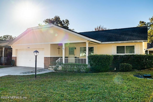 ranch-style house featuring covered porch, a front yard, and a garage