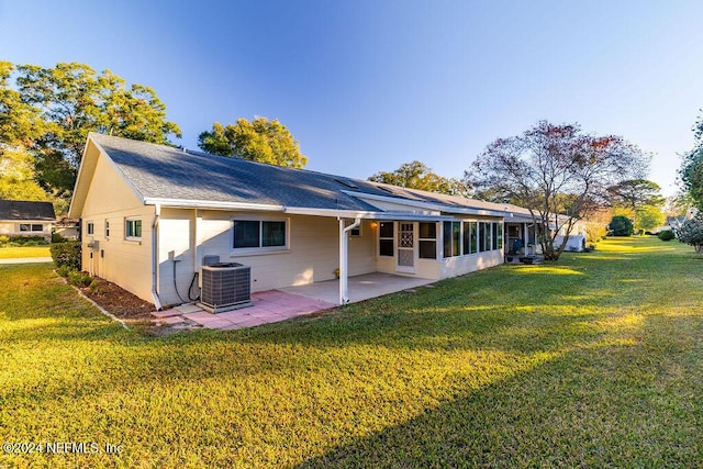 rear view of house with a lawn, a patio area, a sunroom, and cooling unit