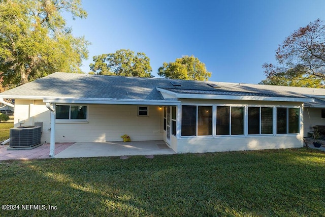 rear view of property featuring a sunroom, a patio, a lawn, and central air condition unit