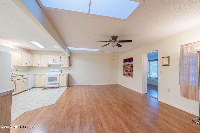 kitchen with a skylight, ceiling fan, white appliances, and light wood-type flooring