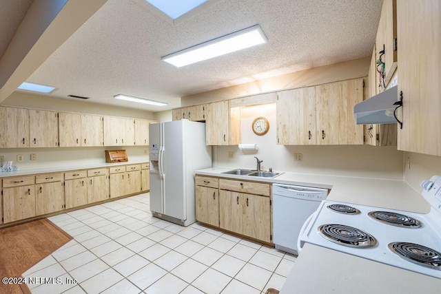 kitchen with a textured ceiling, white appliances, sink, and light brown cabinetry