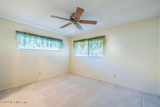 empty room featuring a textured ceiling, ceiling fan, and light carpet