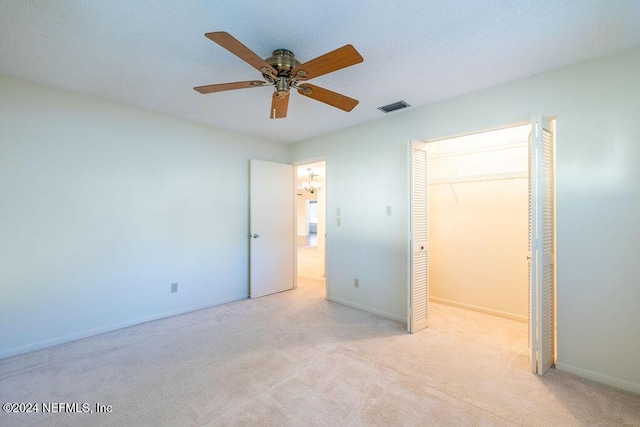 unfurnished bedroom with light carpet, a closet, and ceiling fan