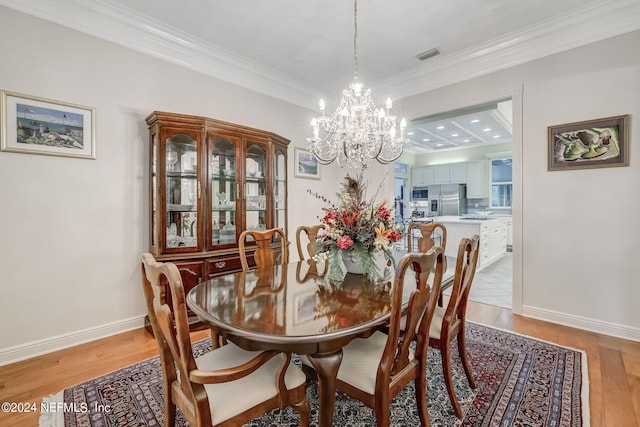 dining space with crown molding, light hardwood / wood-style floors, and a notable chandelier