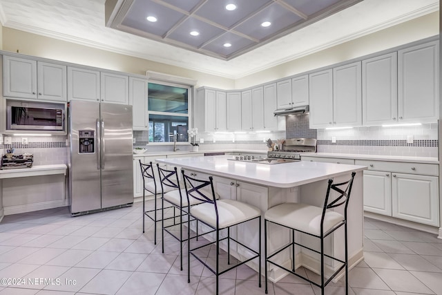 kitchen with a center island, stainless steel appliances, light tile patterned floors, a breakfast bar, and white cabinets