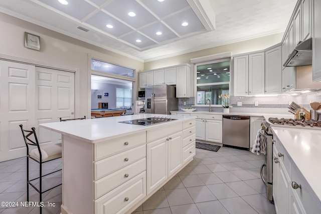 kitchen with a kitchen bar, appliances with stainless steel finishes, light tile patterned floors, a center island, and white cabinetry