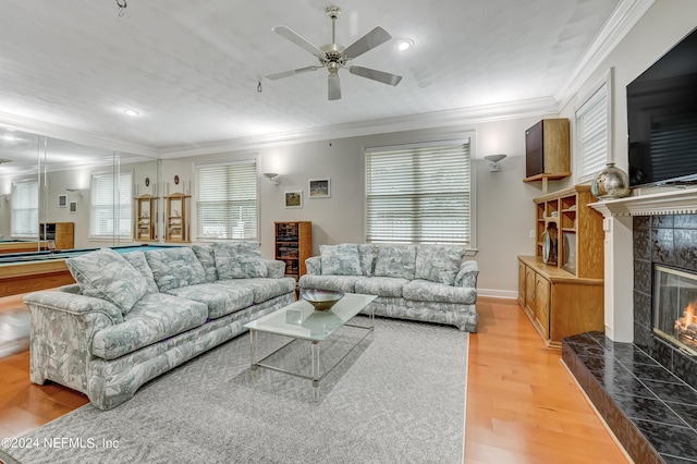 living room with a tile fireplace, ceiling fan, ornamental molding, pool table, and light hardwood / wood-style floors