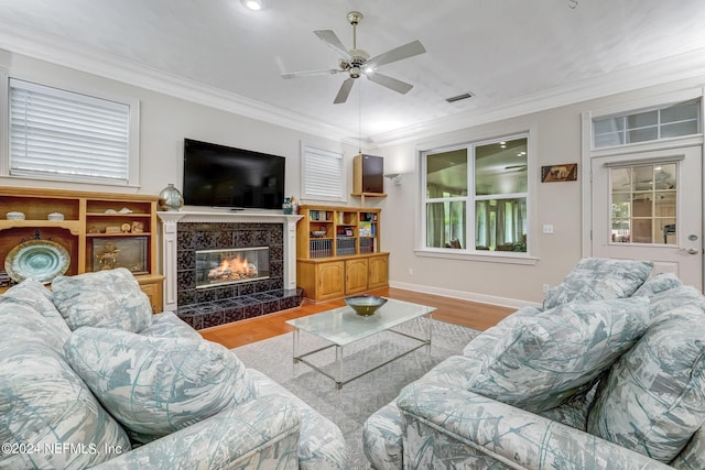 living room with ceiling fan, a premium fireplace, ornamental molding, and light hardwood / wood-style flooring