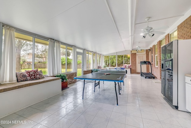 game room featuring ceiling fan, brick wall, and lofted ceiling