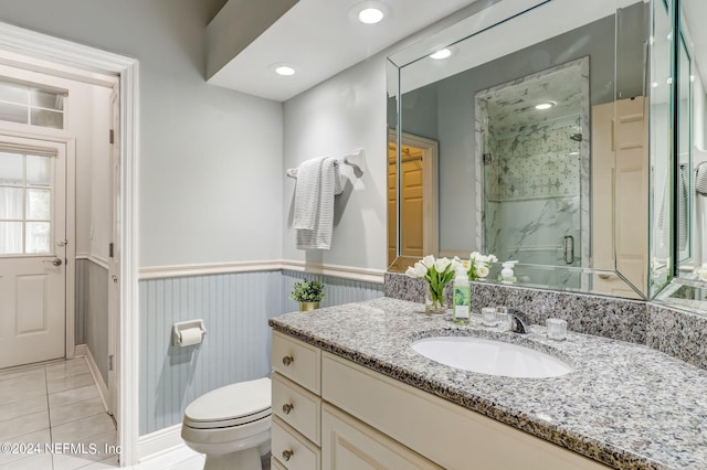 bathroom with tile patterned floors, vanity, a shower with shower door, and toilet